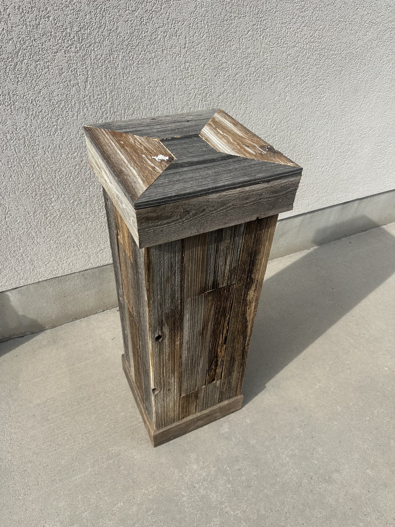 A tall, tapered barnwood pedestal with a mitered peaked cap