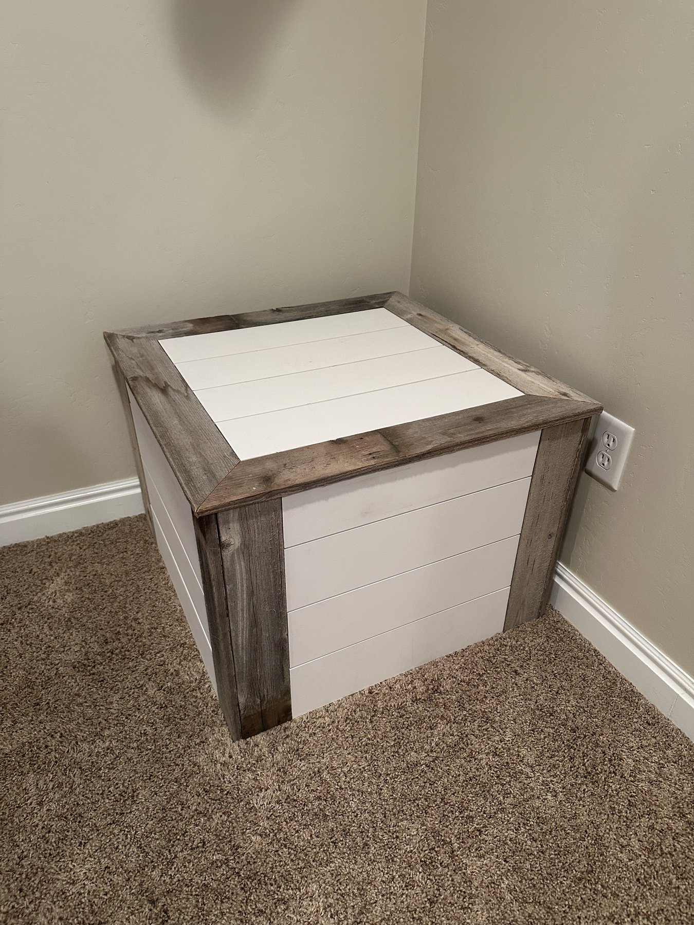 A low square table with painted white shiplap panels and weathered barnwood corner posts